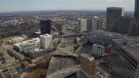 aerial drone shot slowly flying over the highway in downtown atlanta, georgia as rush hour traffic moves between the skyscrapers on a winter day