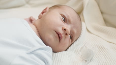 close up of a cute newborn baby lying on bed and moving 1