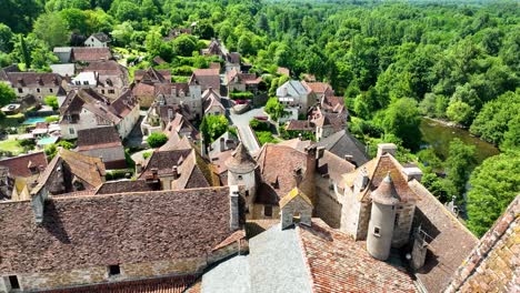 Small,-medieval-village-situated-next-to-a-river,-flowing-through-a-rich-forest-in-the-heart-of-France