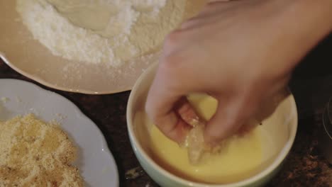 Preparing-A-Yummy-Crispy-Chicken-Fillet-Dipping-The-Thin-Sliced-Meat-Into-The-Beaten-Egg-Then-Coating-It-With-Bread-Crumbs---Close-Up-Shot