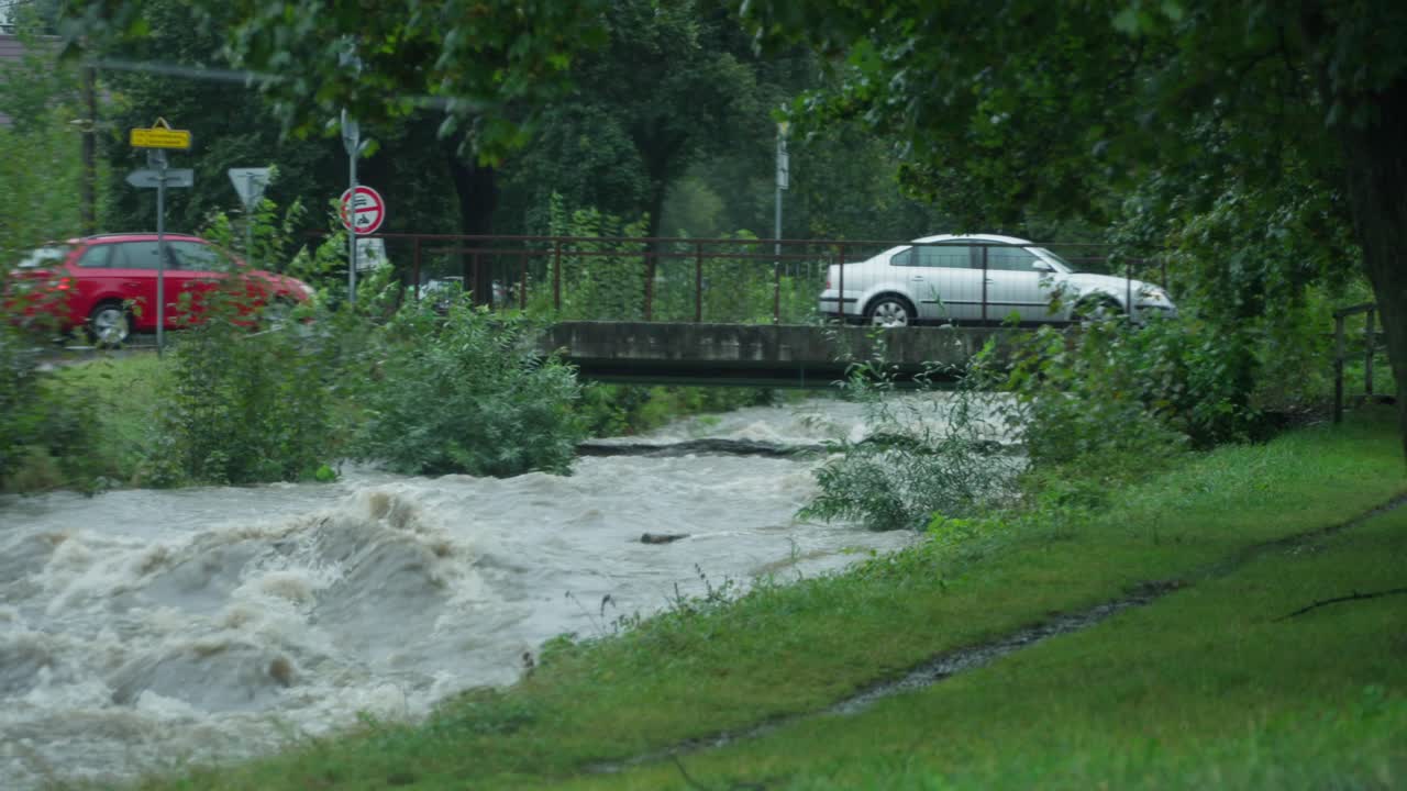 강의 강한 흐름과 선 사람들이 지켜보는 다리를 가로지르는 자동차