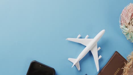 White-plane-model,-smartphone-and-passport-with-copy-space-on-blue-background