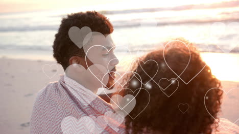 animation of hearts moving over diverse couple in love embracing on beach in summer