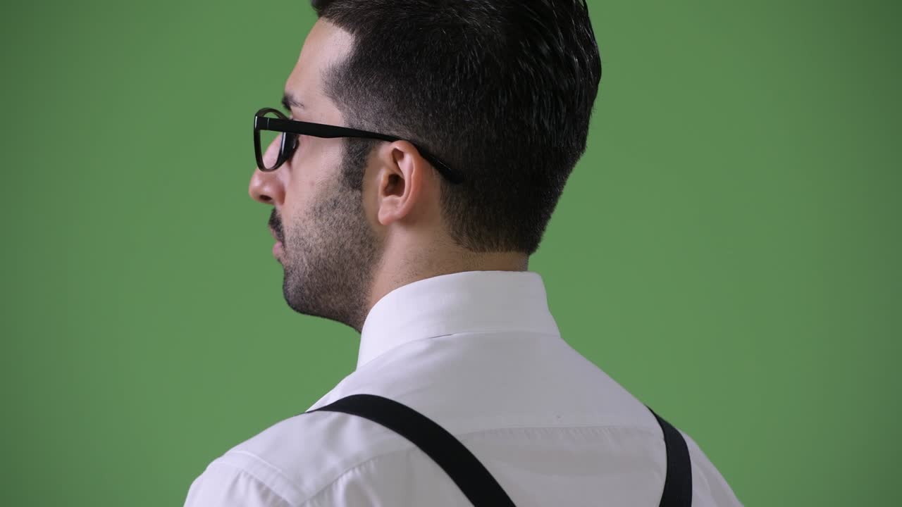 Young handsome bearded Persian businessman against green background