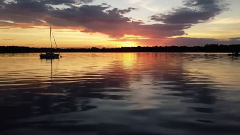 a serene sunset over calm waters with a sailboat silhouetted against the vibrant sky, capturing the beauty of nature's transition from day to night
