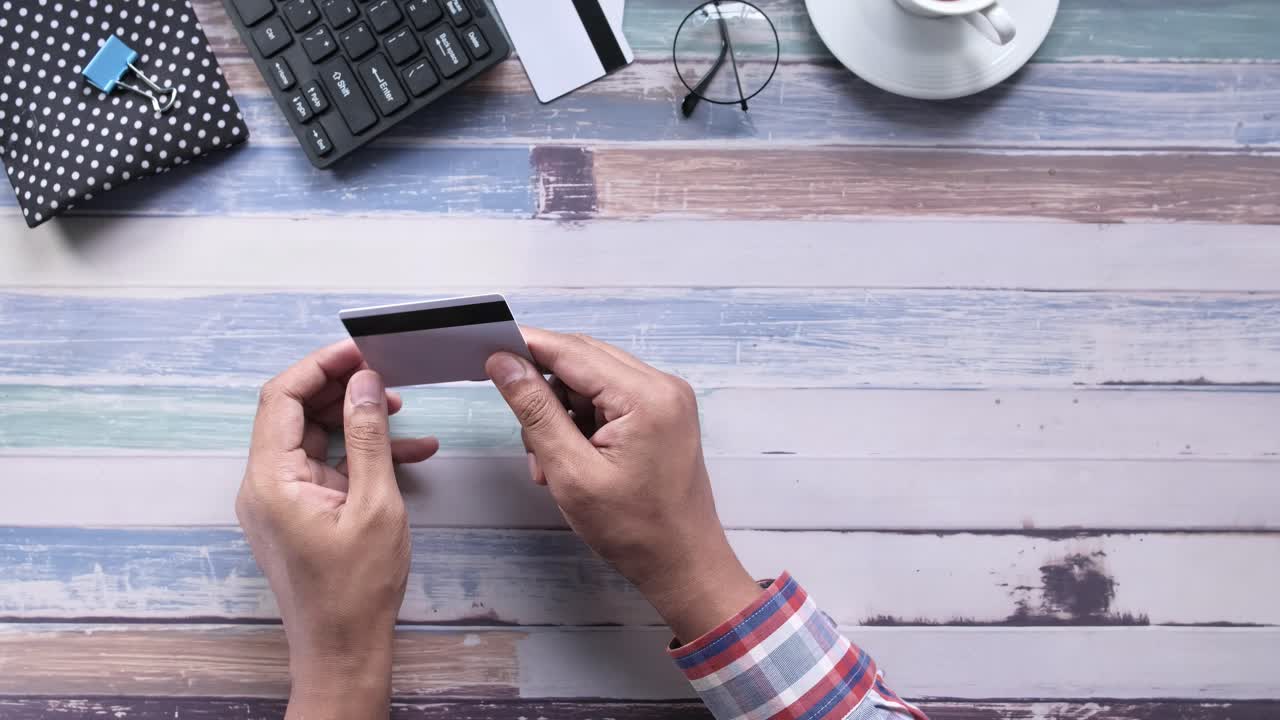 persona sosteniendo una tarjeta de crédito en un escritorio de madera