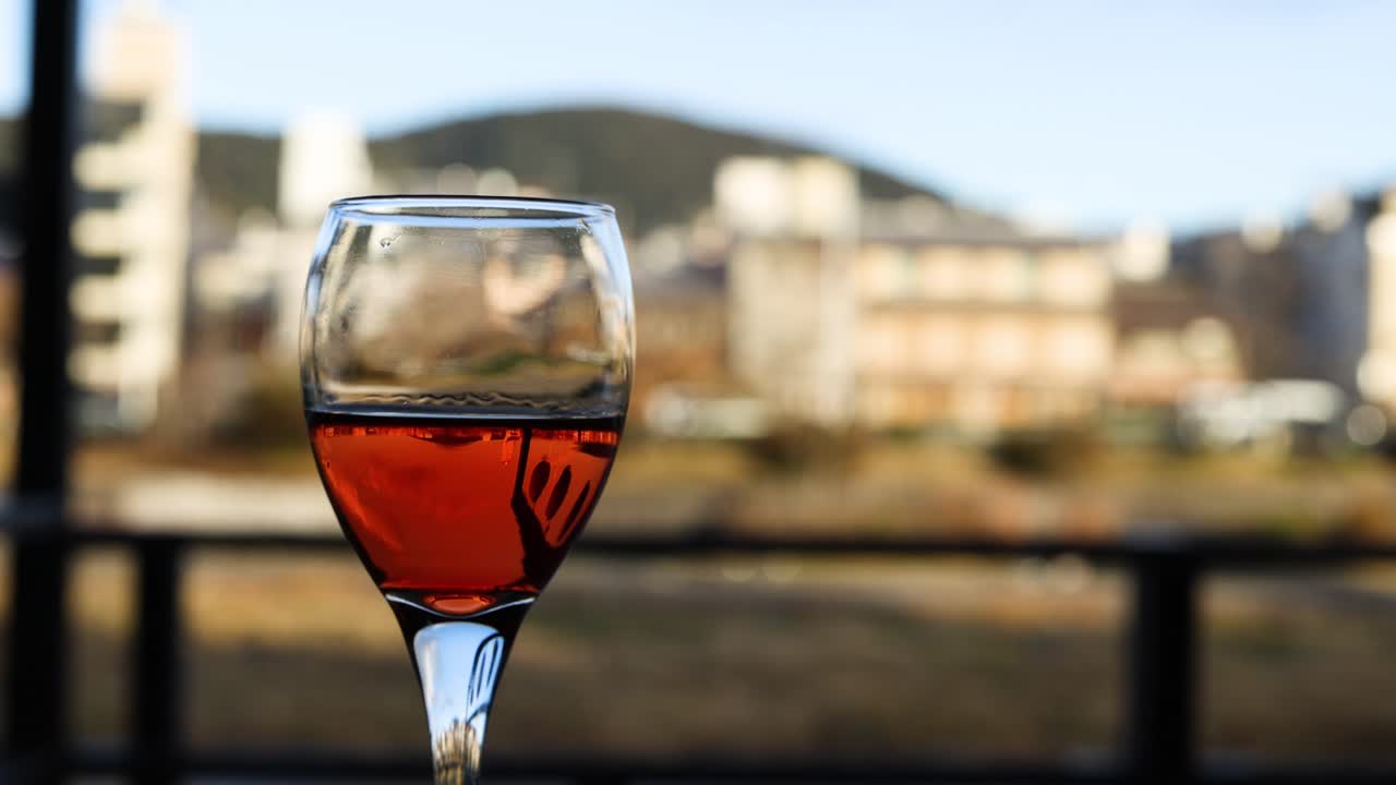 Un calice di vino sembra fluttuare su uno sfondo urbano
