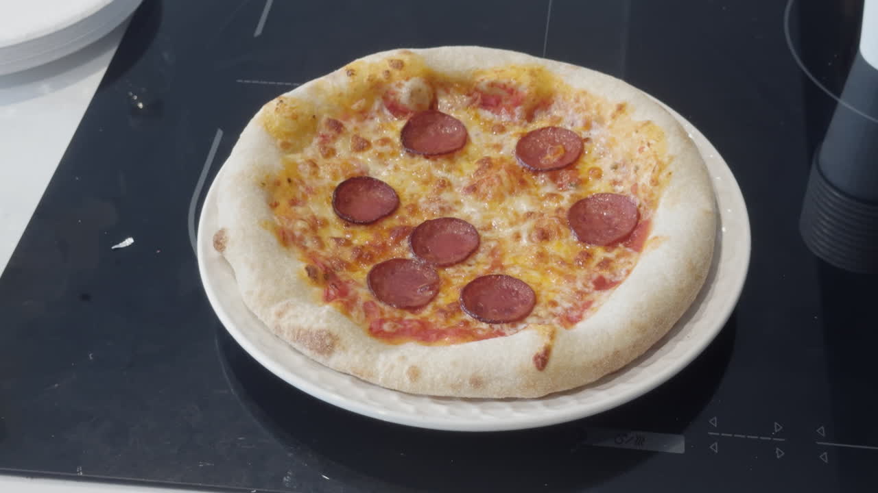 A tasty homemade pizza with fresh dough, cheese, and pepperoni is cooked perfectly and rests on a stovetop