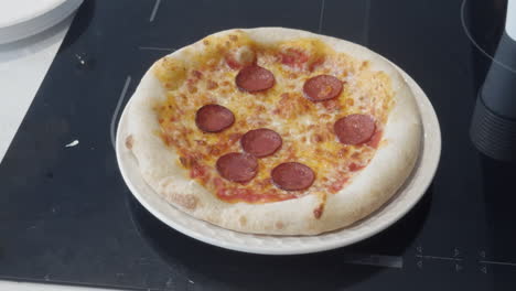 a tasty homemade pizza with fresh dough, cheese, and pepperoni is cooked perfectly and rests on a stovetop