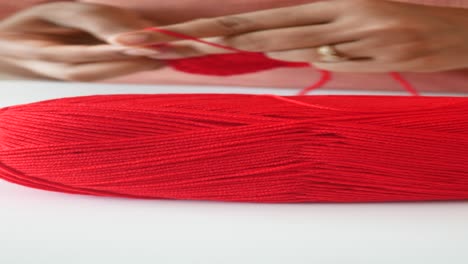 close-up of a woman's hands knitting with red yarn