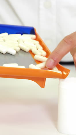 farmacéutico poniendo píldoras en el recipiente en la farmacia