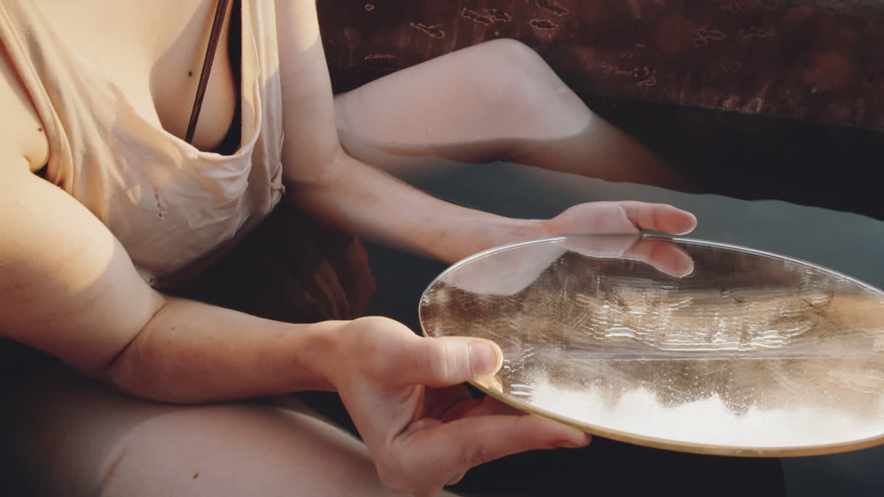 mujer sosteniendo un espejo mientras estaba sentada en una bañera sucia