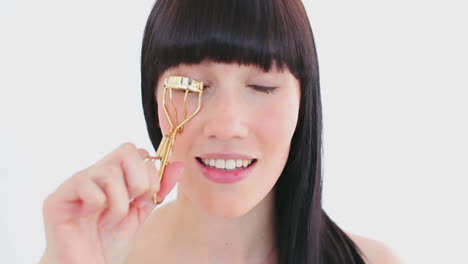 smiling brunette using an eyelash curler