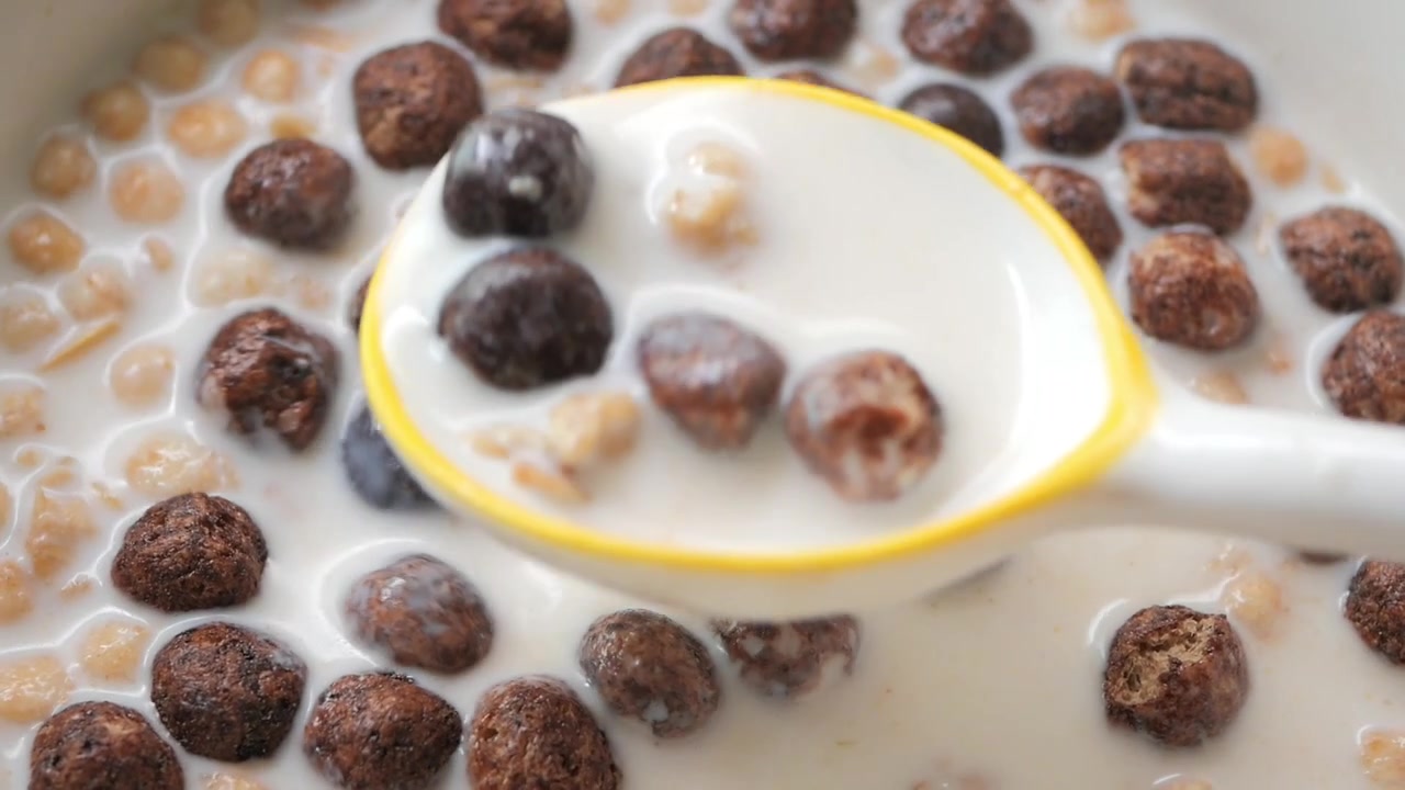 Persona che mangia cereali al cioccolato con latte da una ciotola