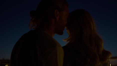 couple enjoying romantic date on terrace at night. man whispering words of love.