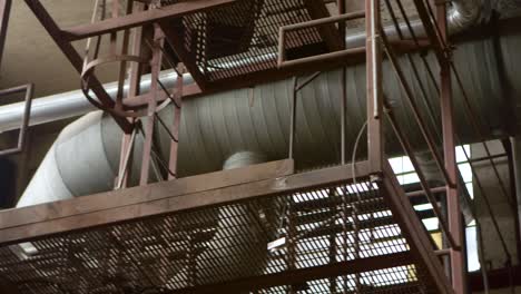 A-pan-shot-of-a-large-air-duct-on-the-ceiling-of-an-abandoned-factory