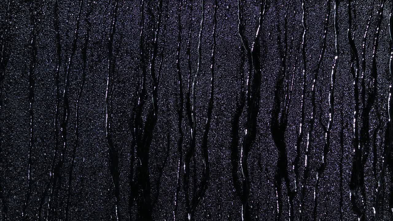 아래로 흐르는 검은 유리 위에 물방울이