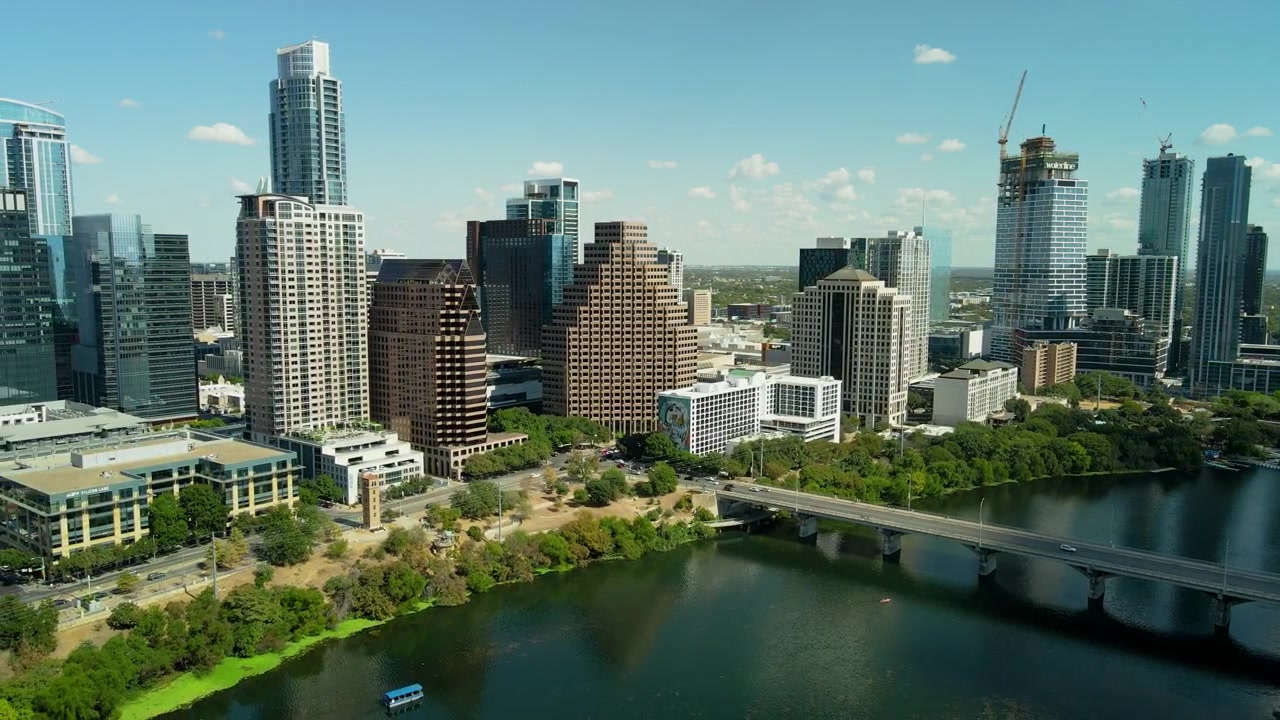 Ripresa aerea con drone con zoom in allontanamento del centro di Austin in una giornata di sole, che rivela la città lungo il fiume Colorado.