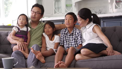 family sitting on sofa at home watching tv shot on r3d