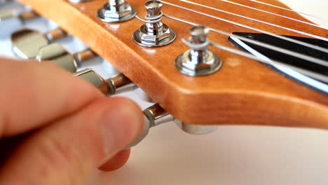 tuning a wood grain electric guitar at the maple headstock