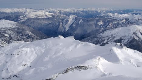 Alta-Vista-Aérea-Del-Paisaje-Montañoso-Invernal-Cubierto-De-Nieve---Día-Soleado