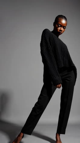 elegant fashion model posing in black off-shoulder sweater and pants