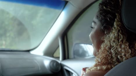 Cute-girl-in-the-front-of-the-car-smiling-at-the-camera