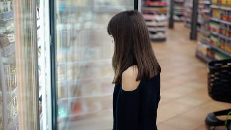 Lovely-teenager-in-the-supermarket,-opens-freezer-door-and-take-and-ice-cream