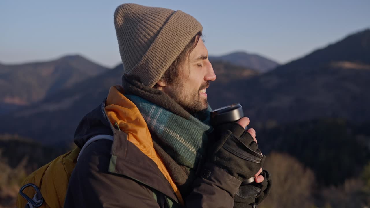 Man drinking hot beverage in the mountains