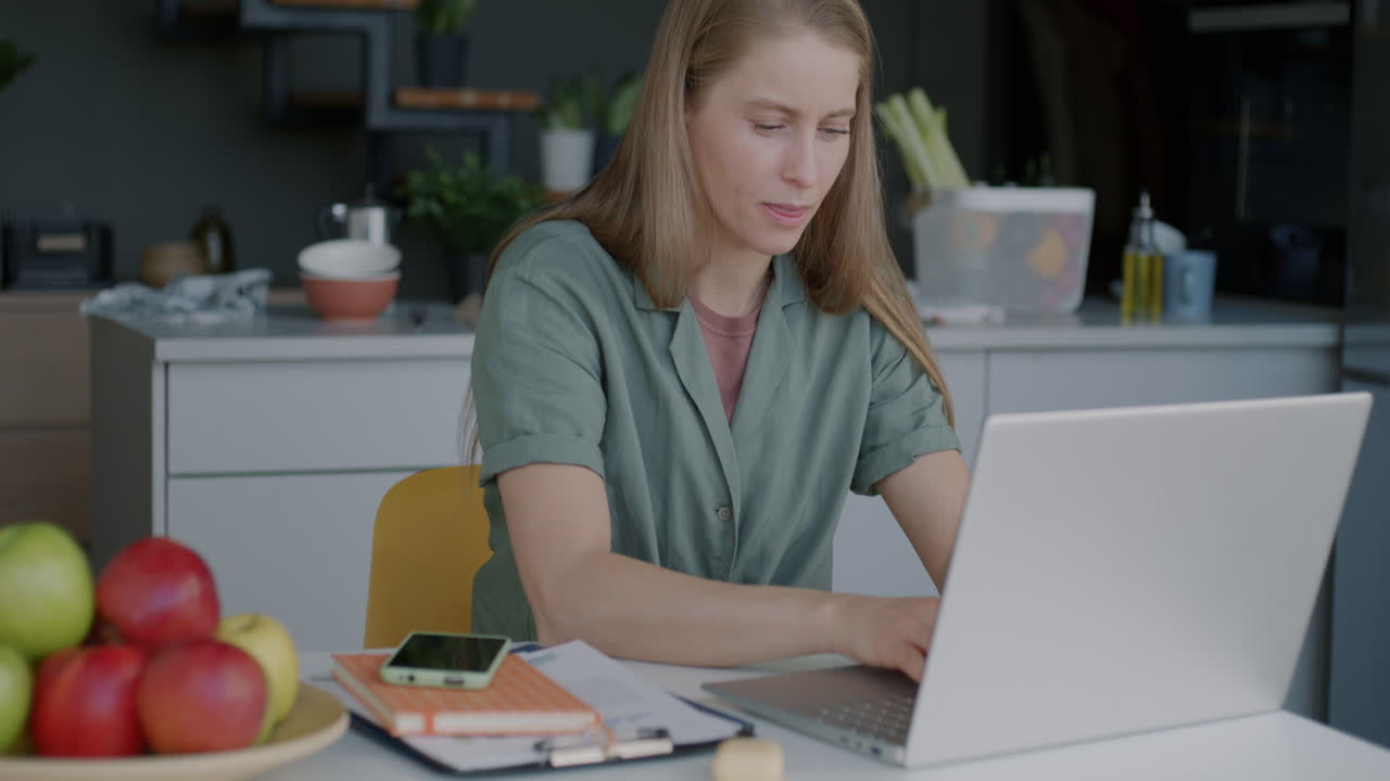 Woman working from home kitchen on laptop