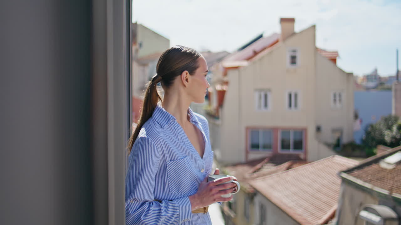 Romantic girl holding tea mug at sun beams city view morning balcony closeup