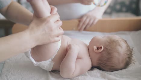 nurse raises infant boy legs practicing hypertonus massage