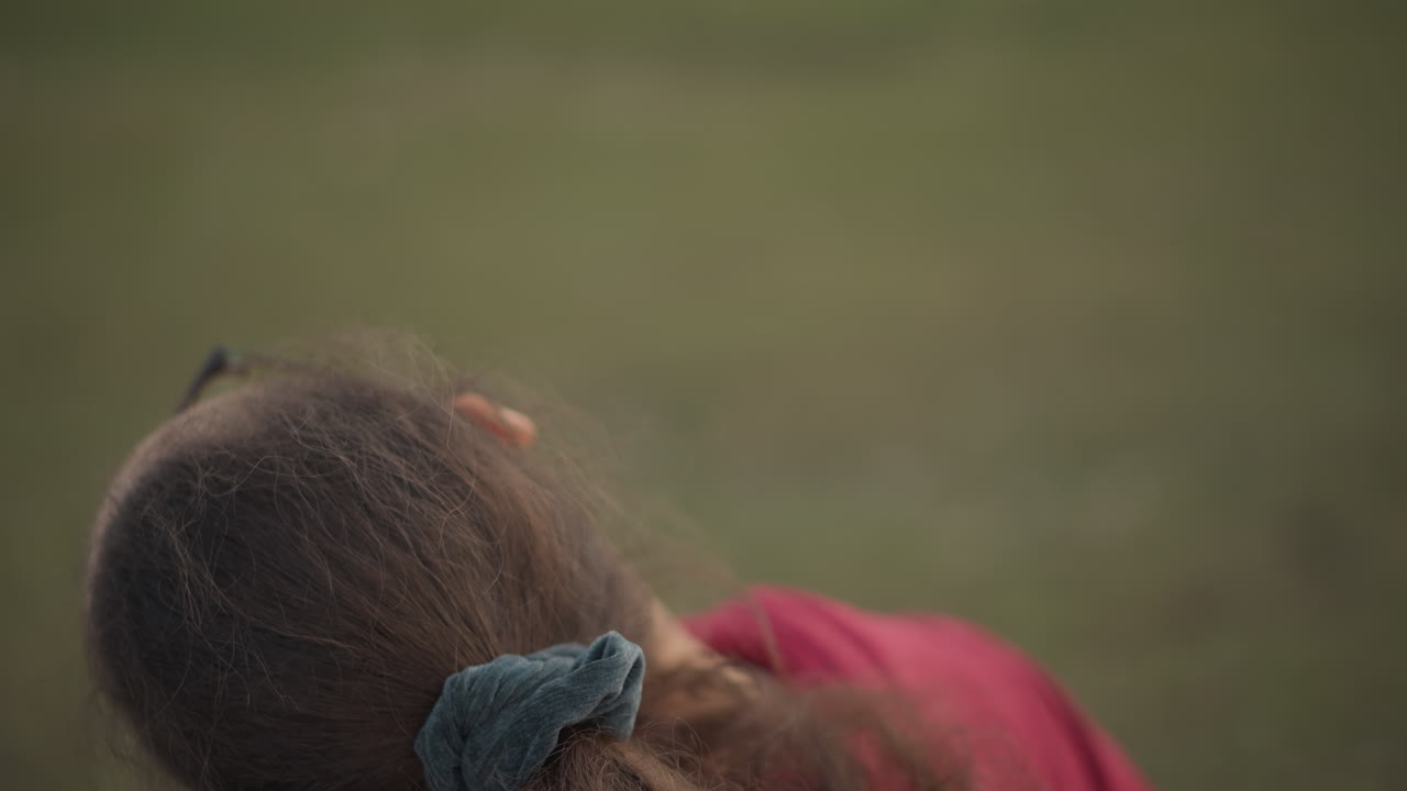 Silently Pondering Young Lady Dressed In Hoodie At Park During Soft Light, Reflective Young Woman In Hoodie Observing Ground Thoughtfully Amidst Muted Colors And Gentle Illumination In Park