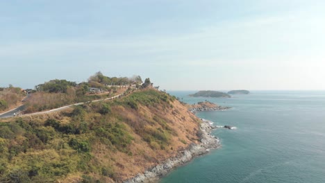 windmill viewpoint over steep hill carrying the road to promphet cape, in phuket, thailand - aerial low angle wide fly-over shot