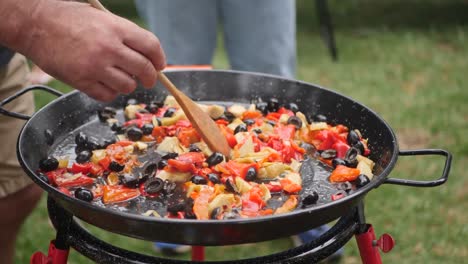 Shot of a man preparing a traditional paella in a garden