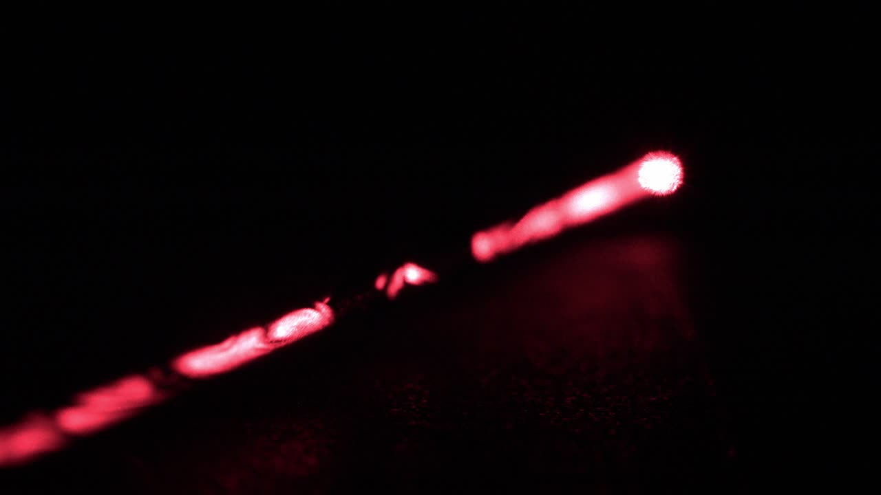 Long Red Laser Beam from Laser Pointer, Rack Focus, Black Background