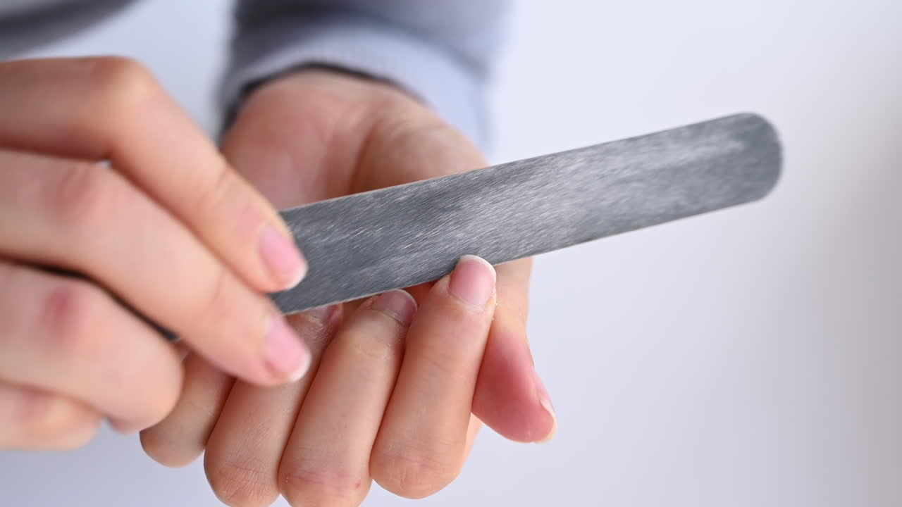 Close up of hands filing nails with a grey nail file during a self care routine
