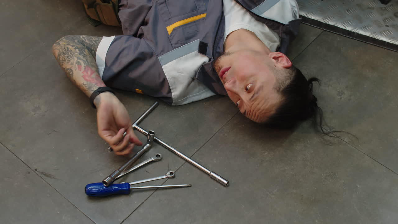 Repairman Wrenching Motorbike Components Lying on Floor