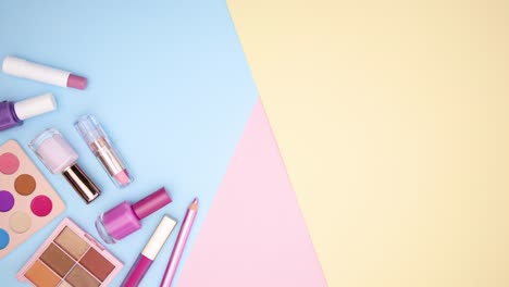 los productos de maquillaje pastel se mueven en la esquina izquierda del fondo pastel - detenga el movimiento