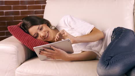 Smiling-woman-using-tablet-on-sofa