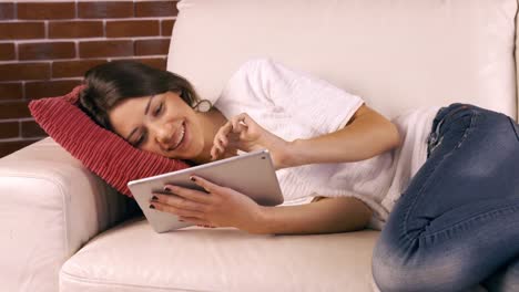 smiling woman using tablet on sofa