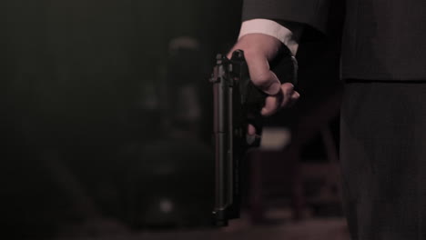 agente secreto mafioso con traje negro sosteniendo una pistola por el torso y luego levantando la pistola