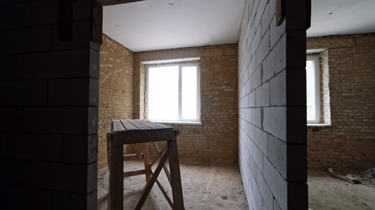 New walls of white bricks are added in the old building. Wooden scaffolding in the rooms of the premise.