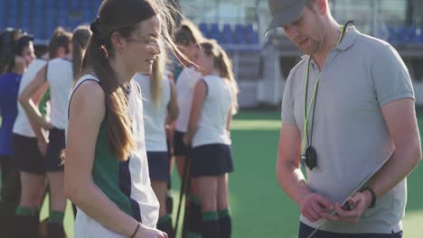 hockey coach explaining game plan to female player in the field