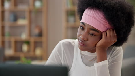 a woman with curly hair sits at a desk and looks down at her laptop