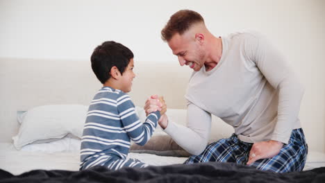 man, boy and arm wrestle for fun in home