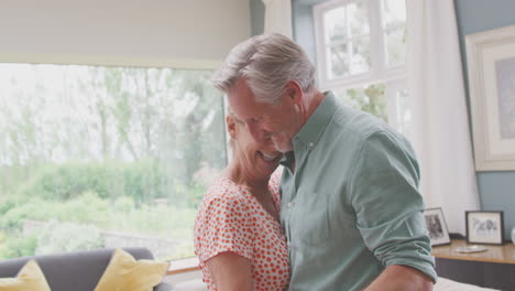 Romantic-Senior-Retired-Couple-Dancing-In-Lounge-At-Home-Together