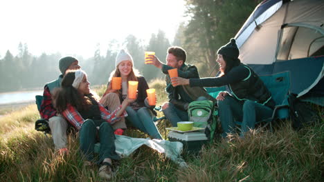 group of friends on a camping trip sitting outside a tent