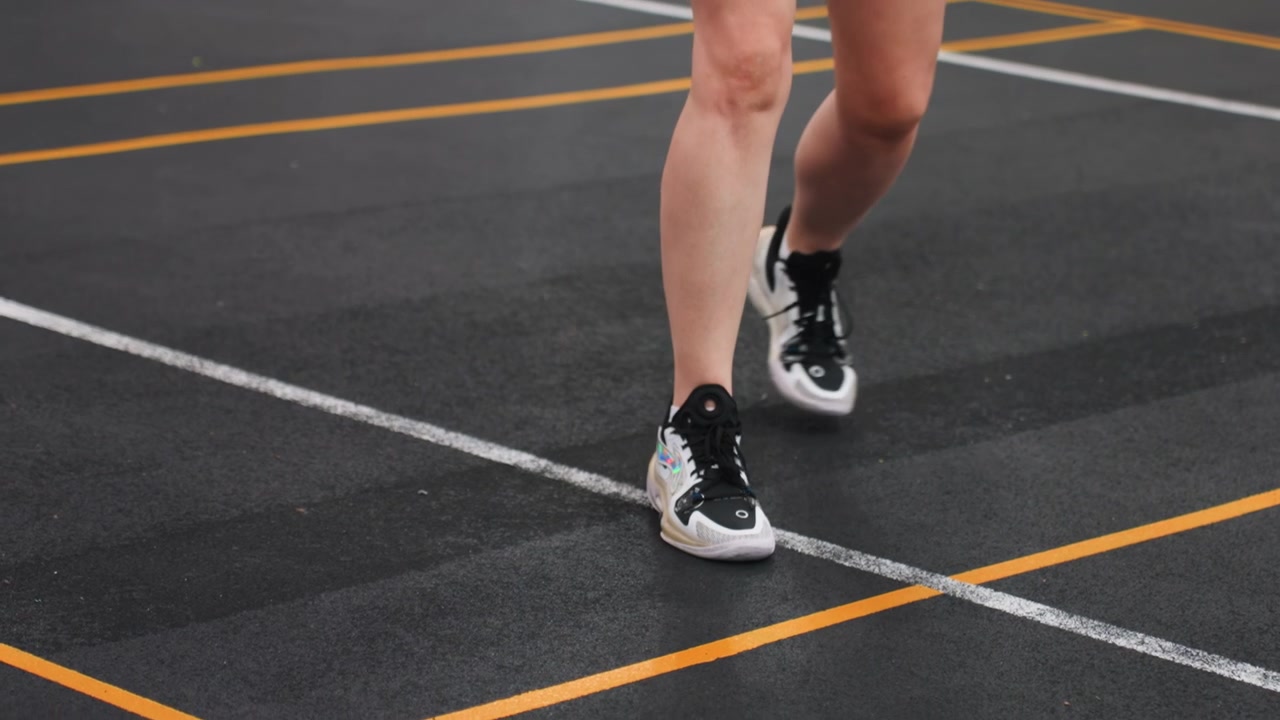 Atleta bianca di badminton con piedi veloci attraverso il campo, esercizio di velocità individuale incentrato su perni e atterraggi, primo piano di gambe e scarpe su pavimentazione marcata, allenamento ad alta energia con enfasi sulla reazione.