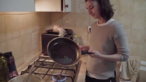 mujer joven engrasando sartén para hacer panqueques